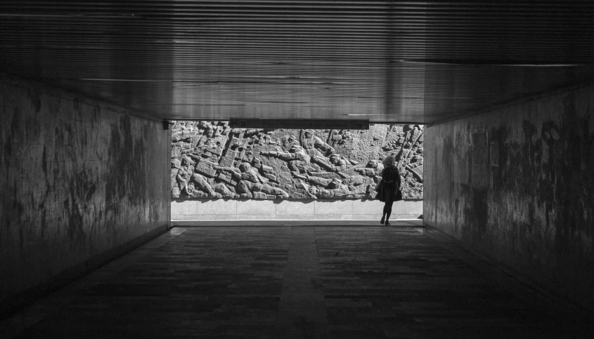 a man is walking down a long hallway in a dark room