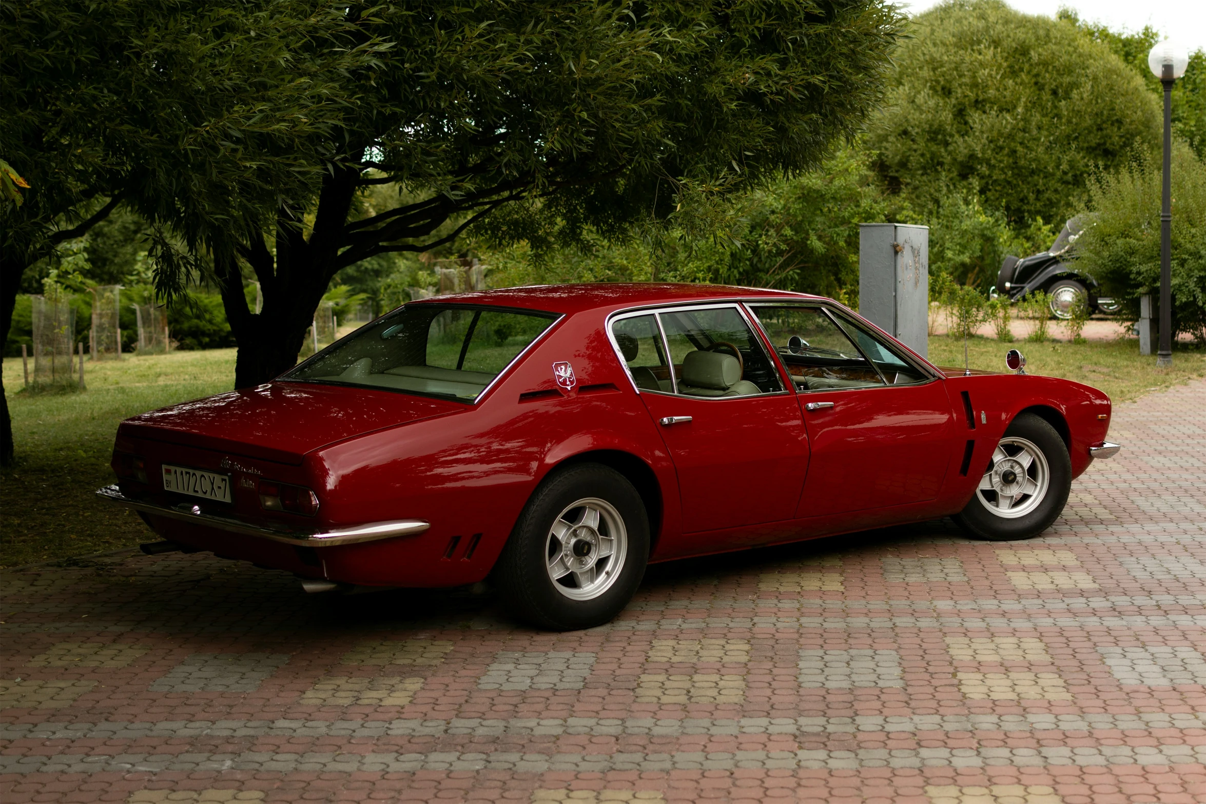 a red sports car is parked near trees