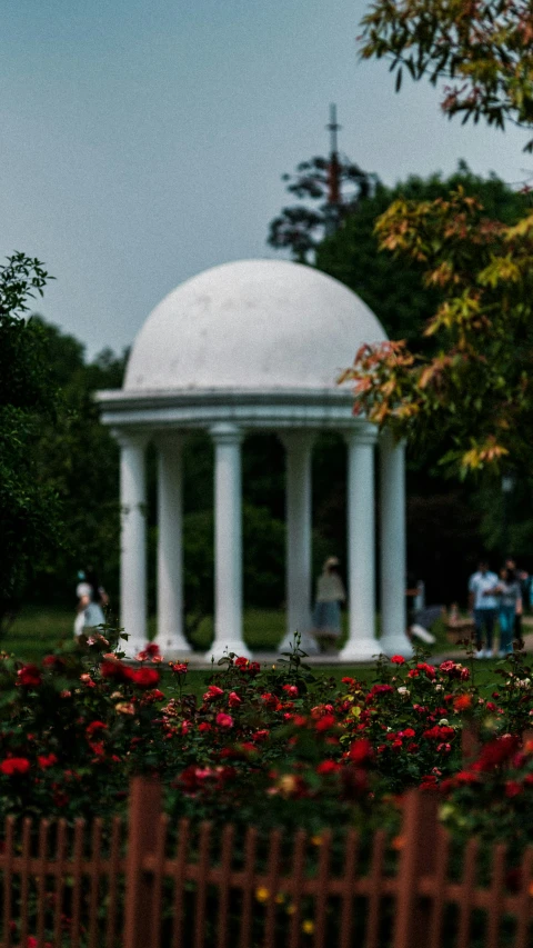 a white building in front of some red flowers