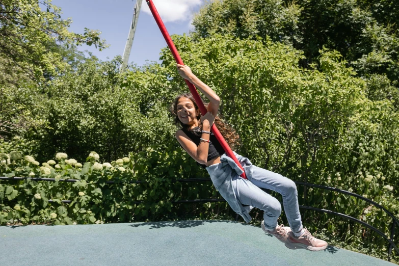 a girl swinging on a pole on a park