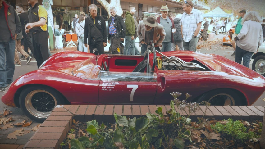 a red race car is shown at a gathering of people