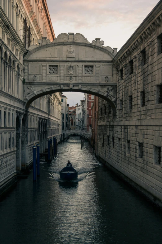 a small boat floating down a narrow river under an overpass