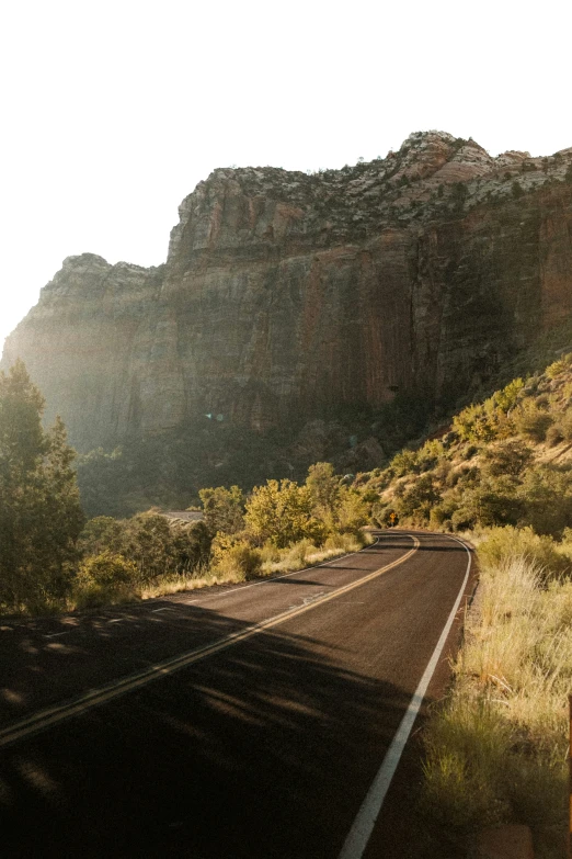 the sun shines through mountains and on road