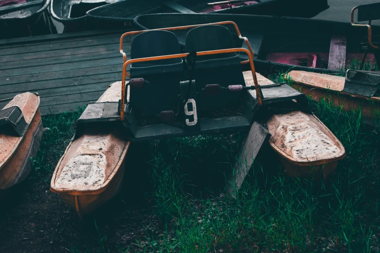 three canoes resting outside in grass on a rainy day