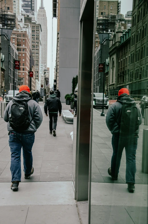 people are walking along a city street while traffic goes by