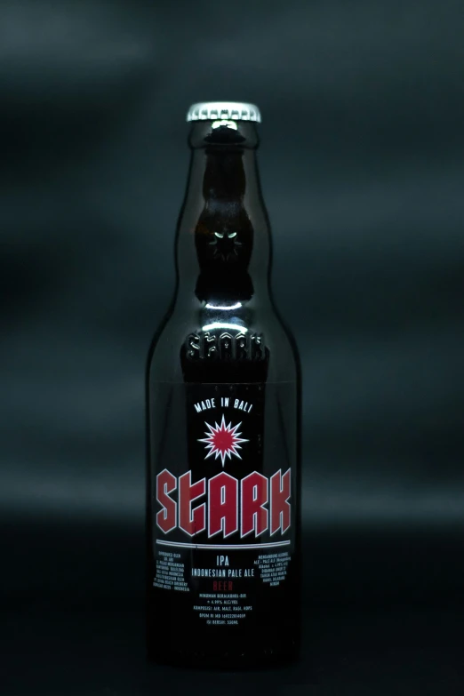 a bottle filled with dark alcohol on a black surface