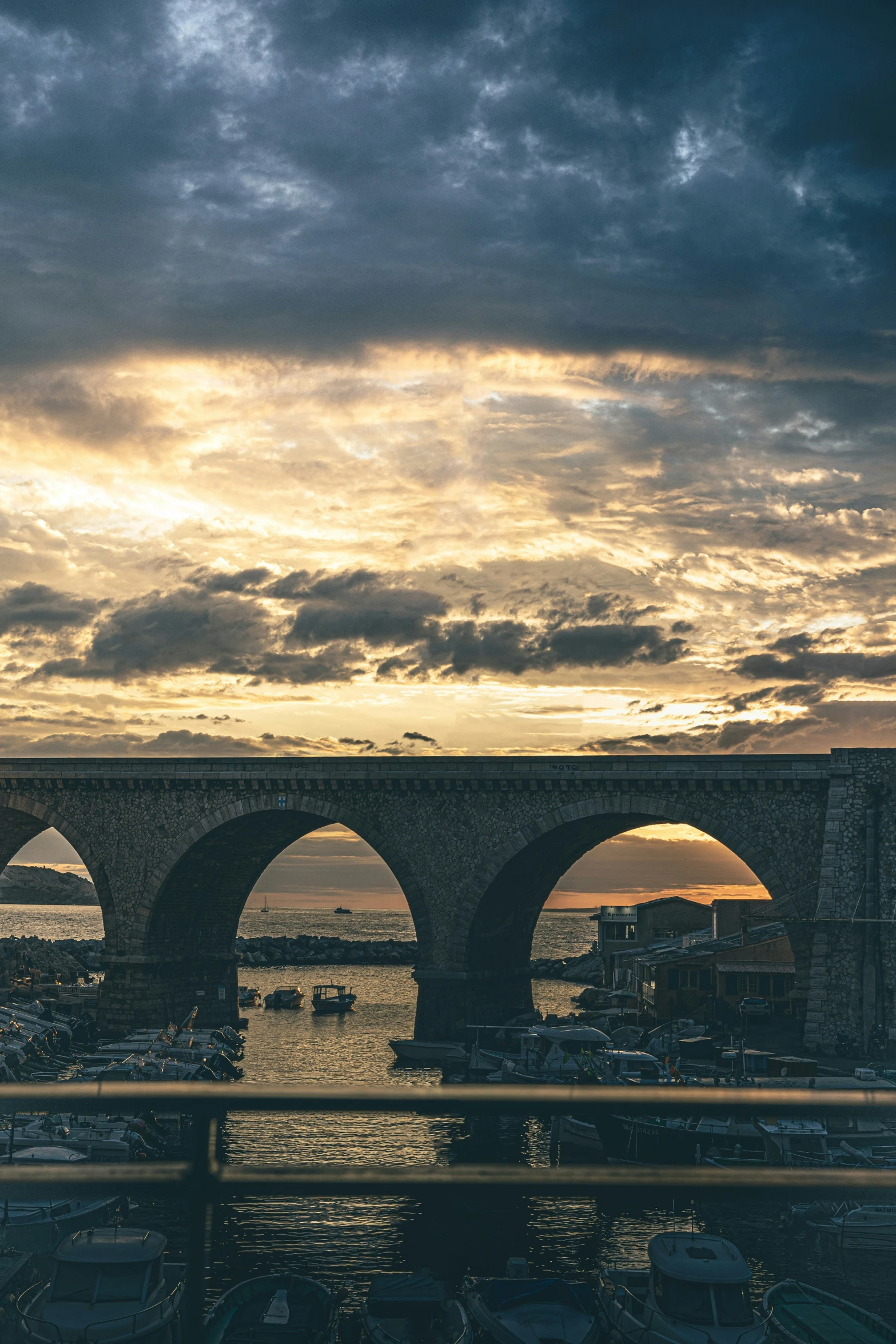 clouds hang over an old bridge during the sunset