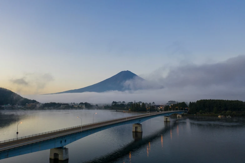 a bridge on the water and a mountain in the background