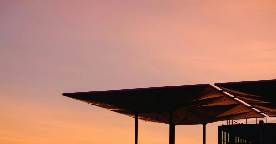 a group of umbrellas are against a sunset sky