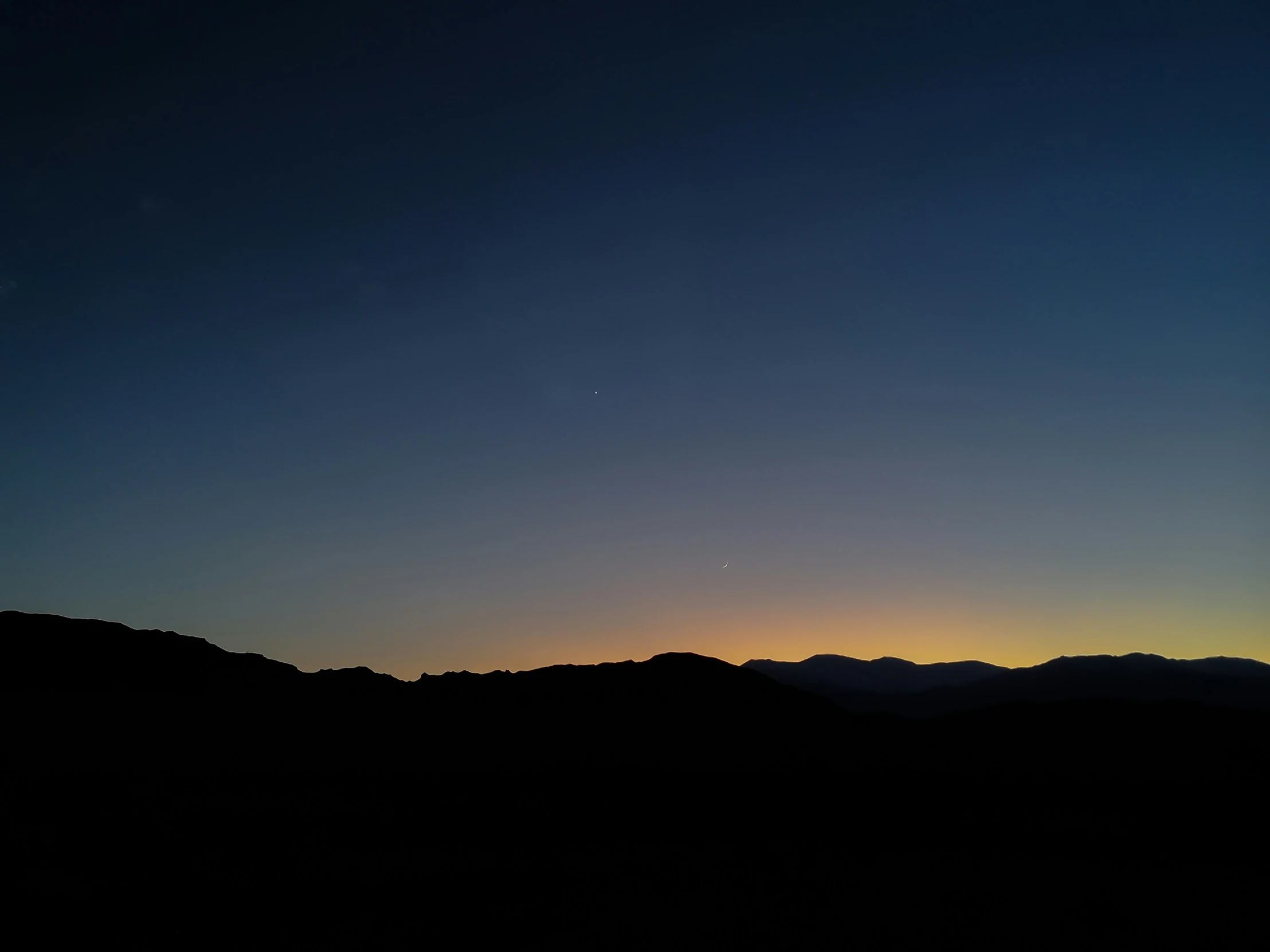 the sky at dusk is dark, showing two moon and two silhouettes