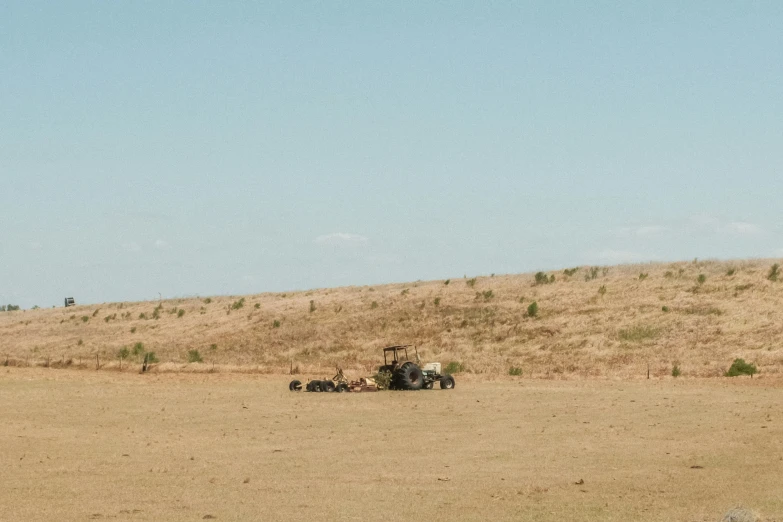 three farm equipment on a dry, grassy area