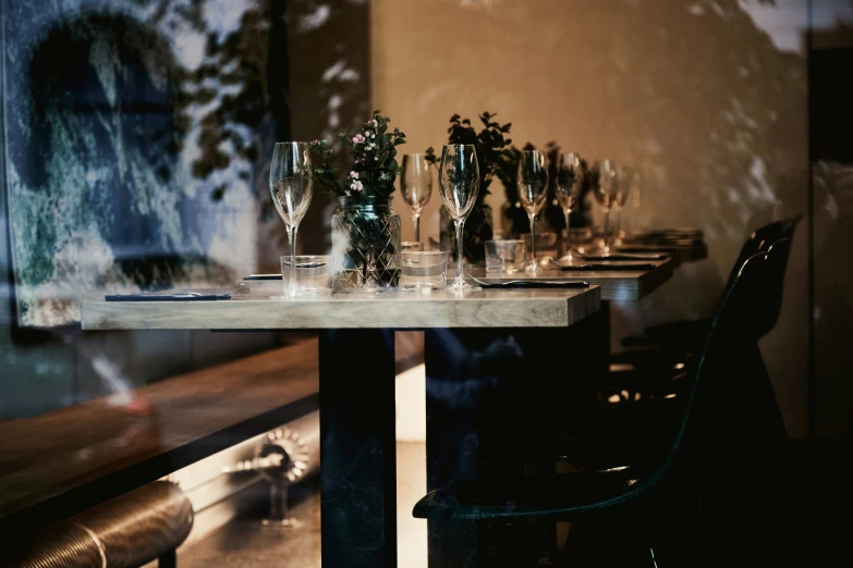 a long table with glassware on it and a few plant's growing from it