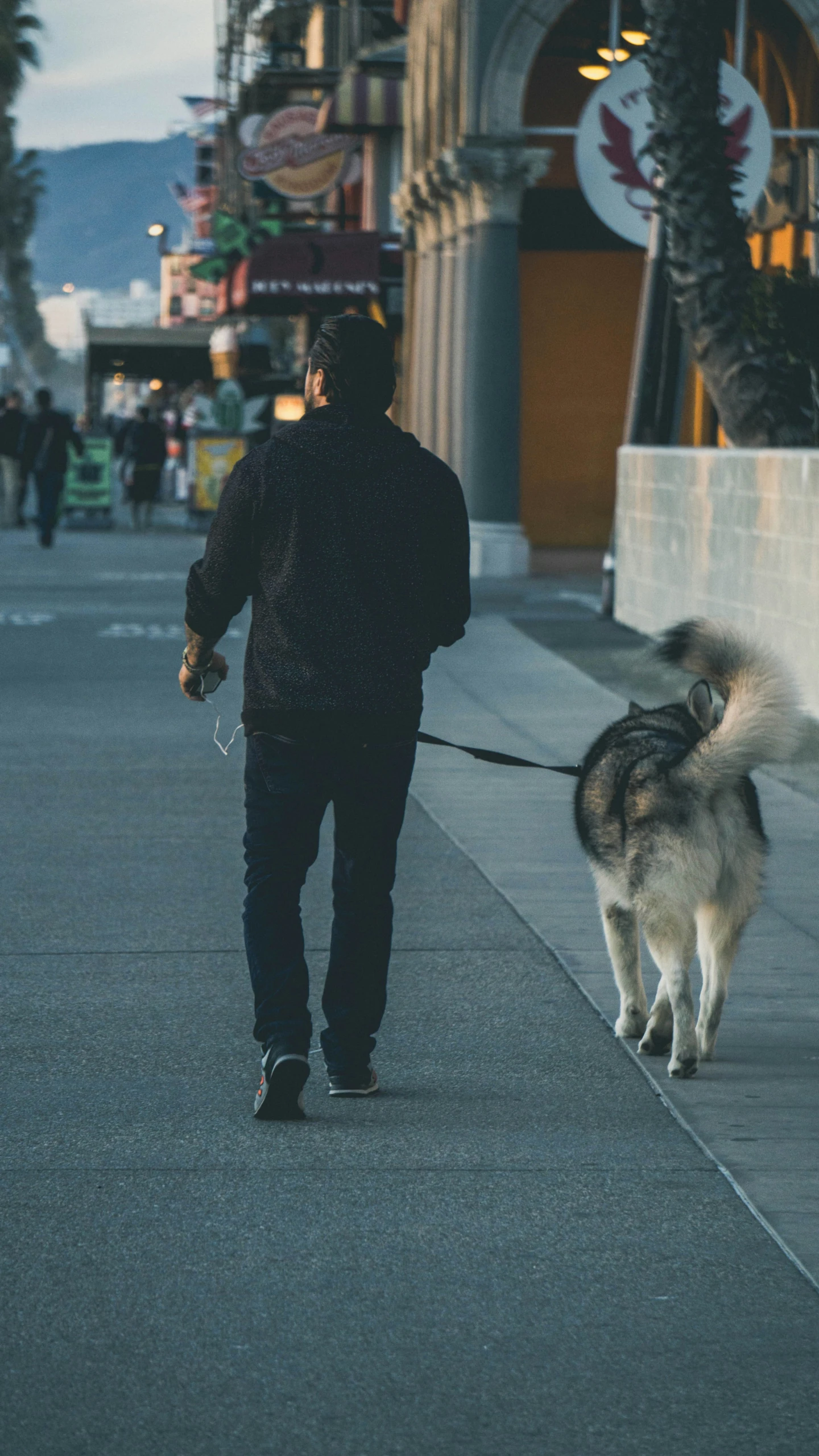 a man walking his dog on a sidewalk