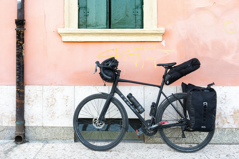 a bicycle is leaning against a wall with a bag on the side of it