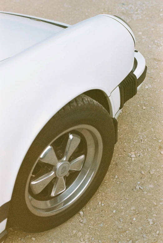 the front wheel of an old car parked on concrete