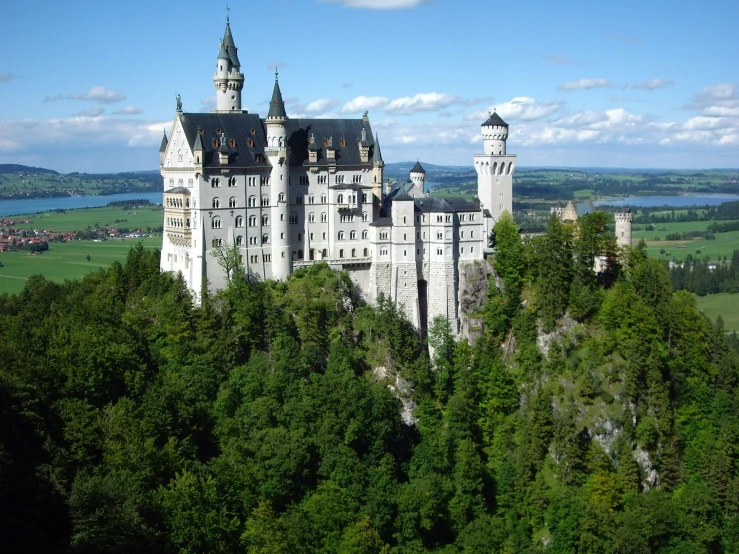 the large castle with towers is nestled high above the forest