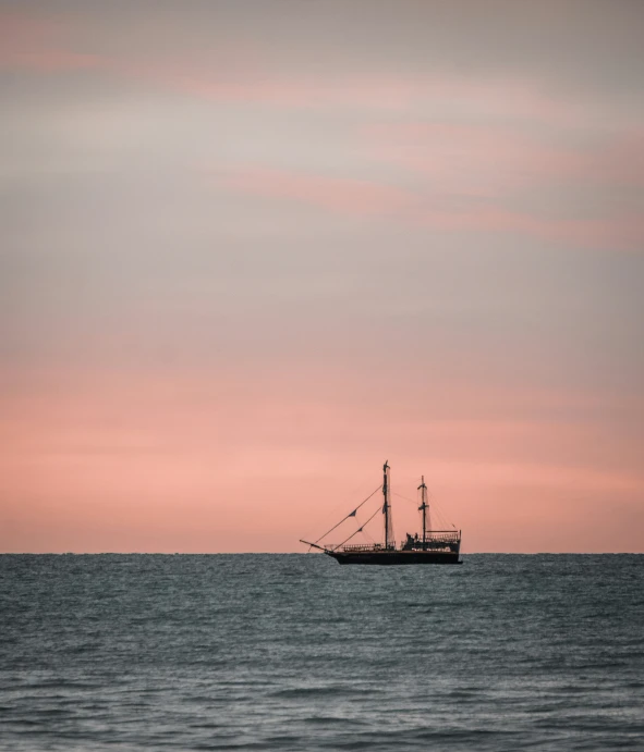 a ship floating through the ocean at sunset