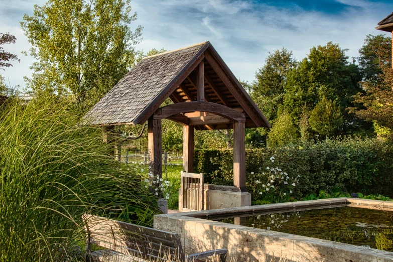 a building with an outdoor pavilion over a pond in the grass