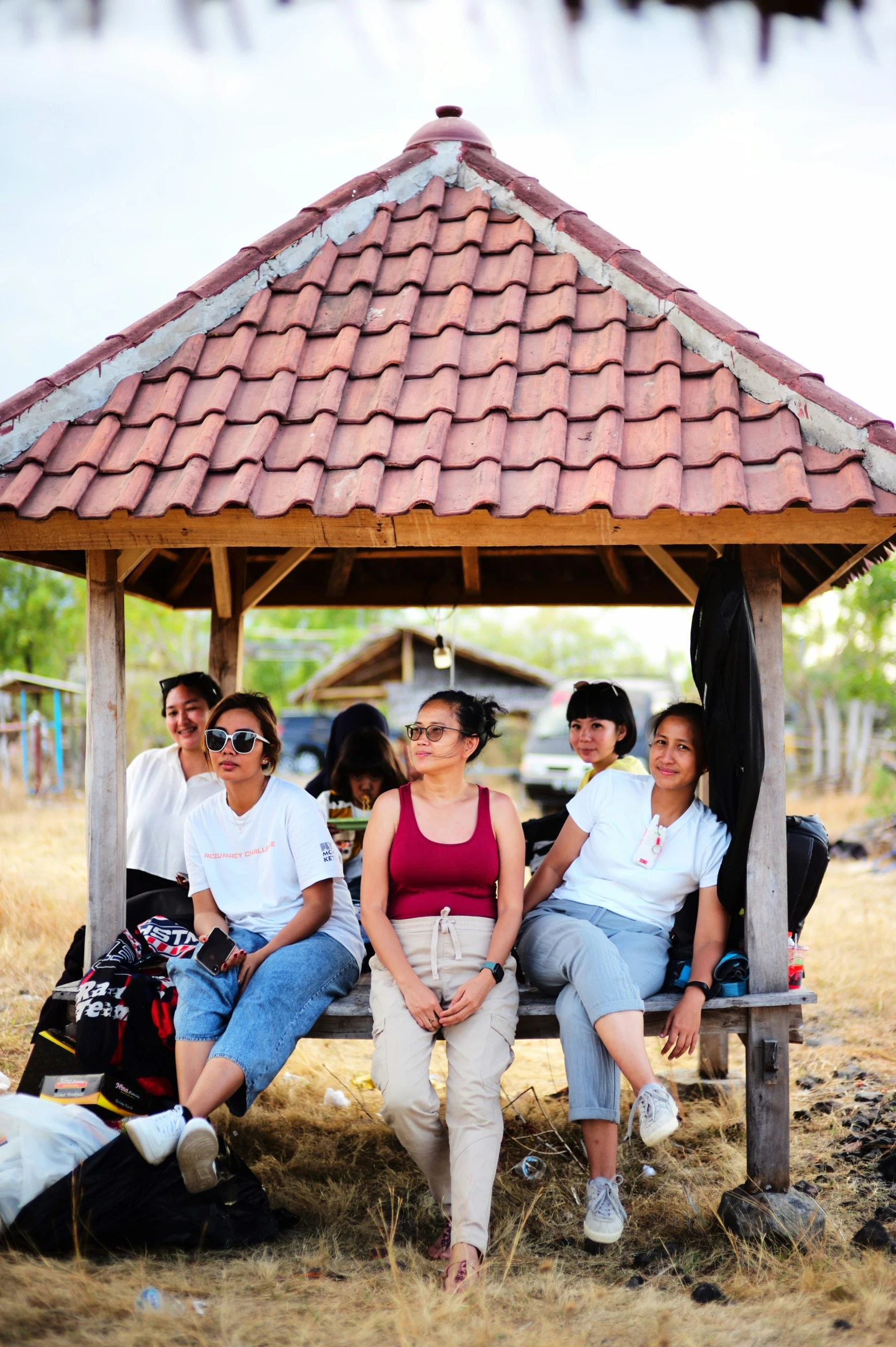 five friends are sitting on a bench in the shade