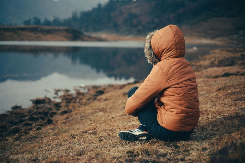 a person sitting by a lake staring at soing in the distance