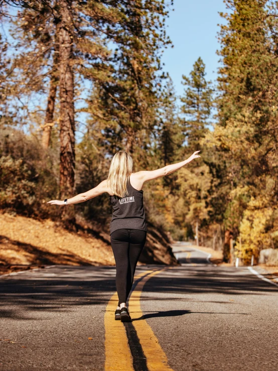 the woman is walking down the road in the forest