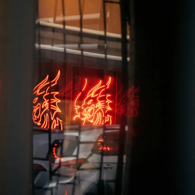 a red neon dragon is reflected in a store window