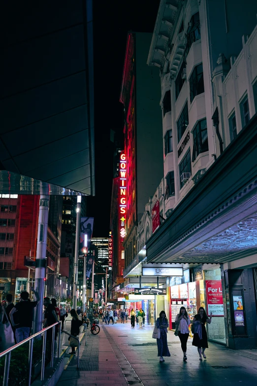 a city street at night with people walking by