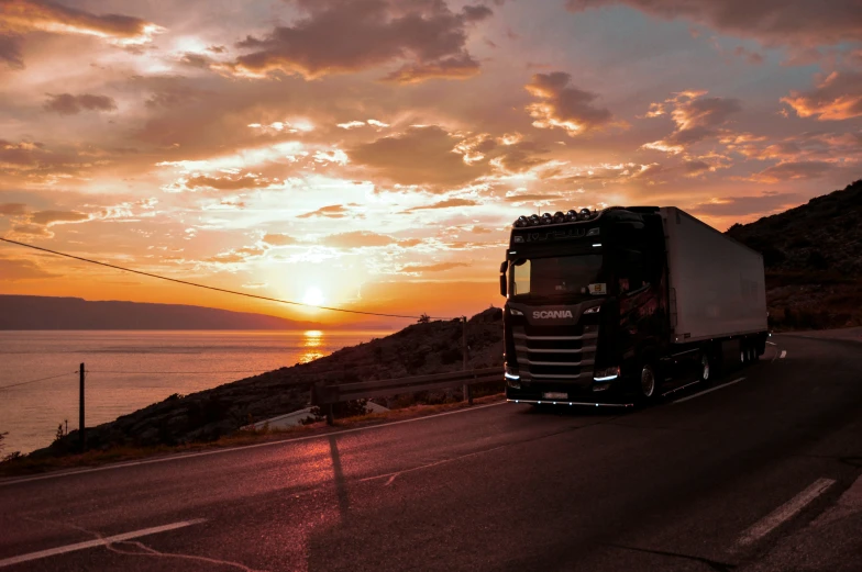 a black truck driving on the road during sunset