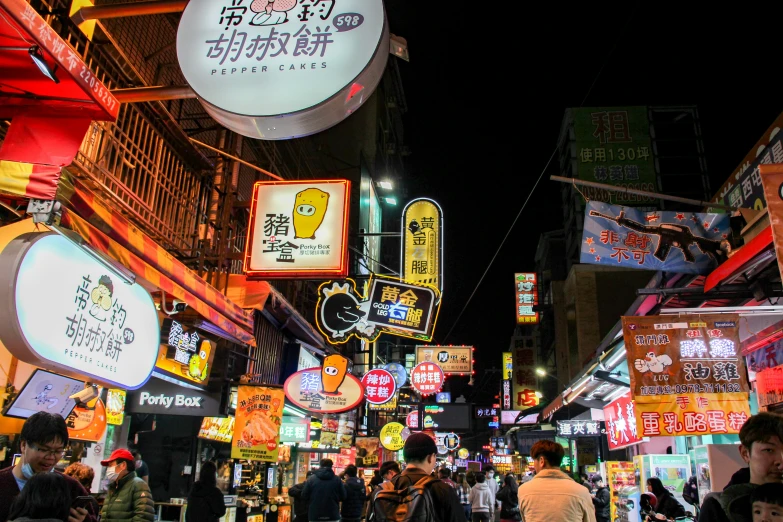 street signs, lights, and people walking on a busy street at night