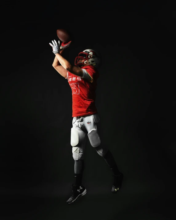 a football player reaching up to catch a ball