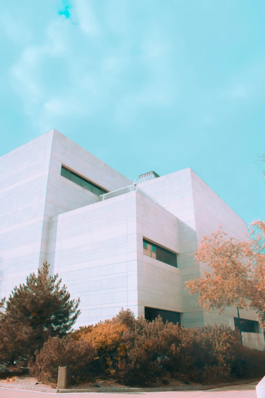 a grey building with trees and bushes surrounding it