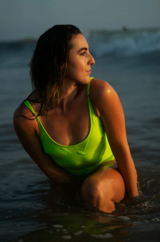 a woman in a yellow bathing suit is squatting in the water