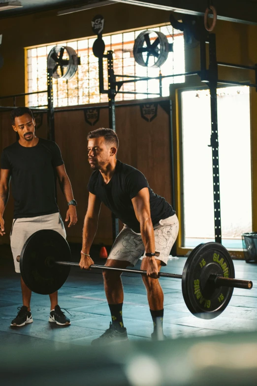 two guys with barbells are in a cross fit gym