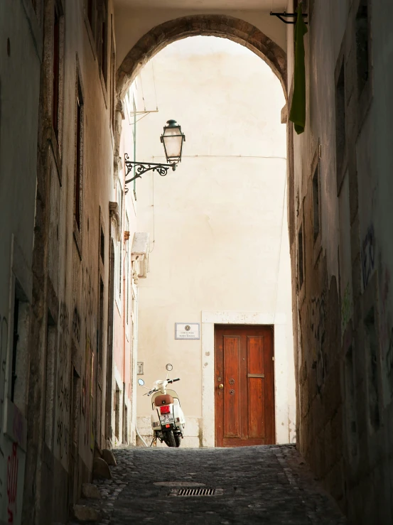 a scooter parked near a door in an old alley way