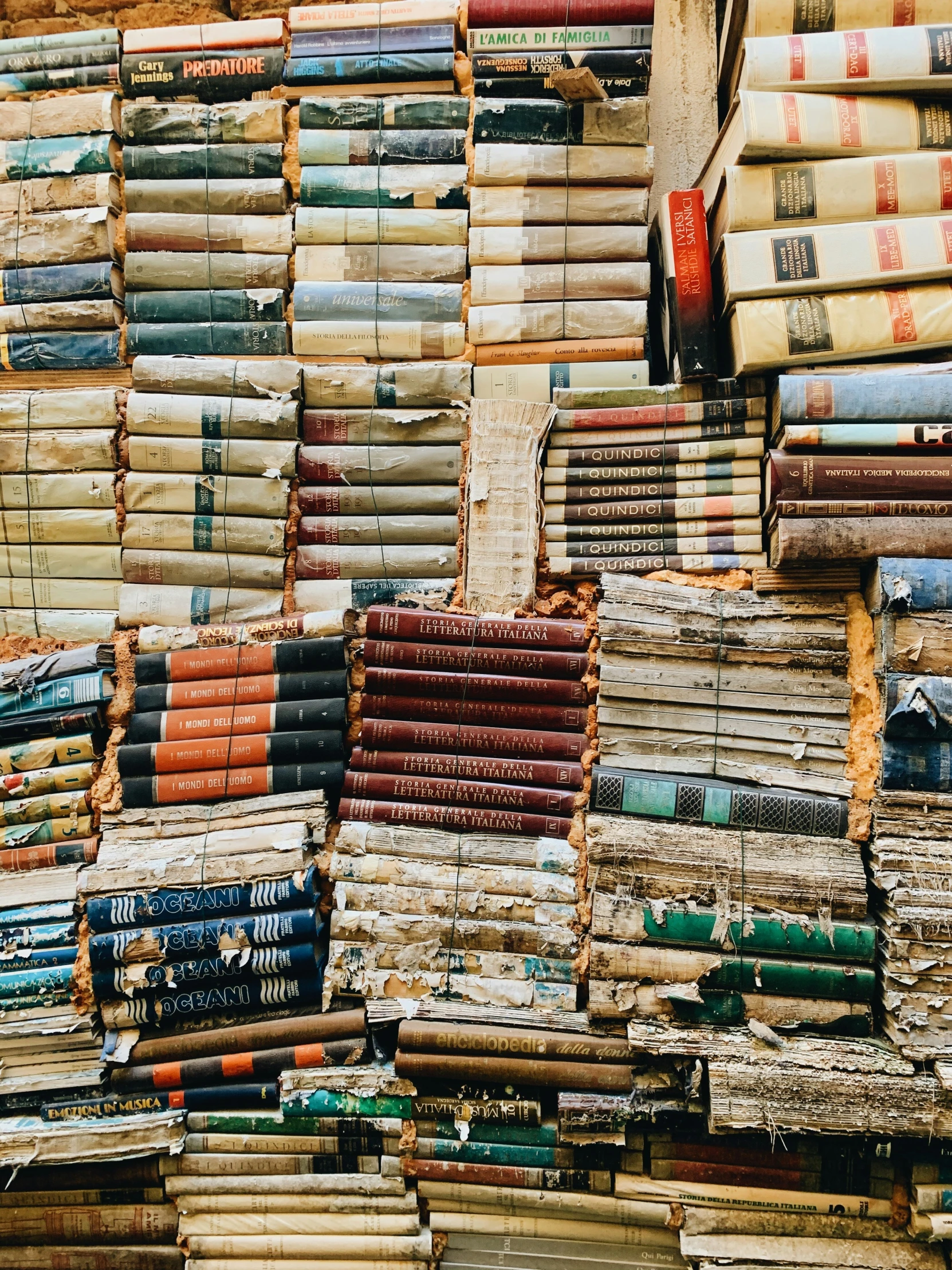 piles of books laid out for sale in front of a building