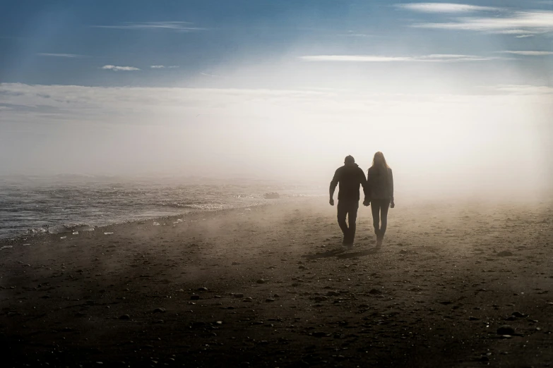 the man and woman walk hand in hand on the beach