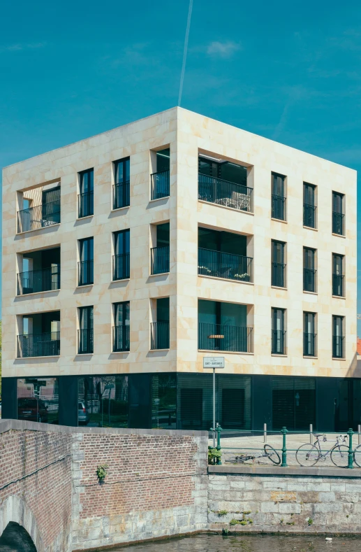 a beige brick building is situated at the side of the river