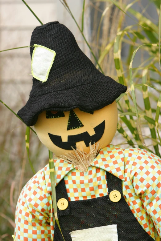 a pumpkin scarecrow doll standing next to some grass