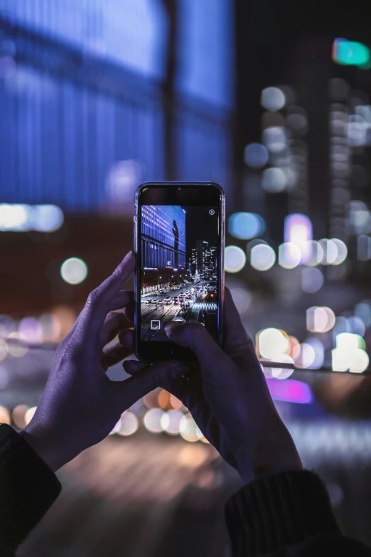a person taking pictures with a cell phone at night