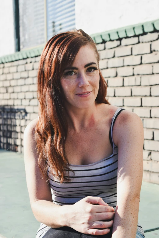 a beautiful young red headed woman sitting on the ground