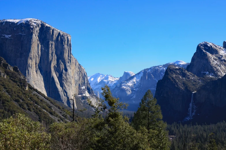 the top of a mountain with trees and mountains in the background