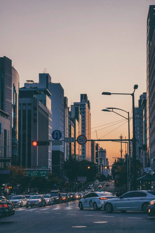 a sunset over a crowded city with cars and people crossing