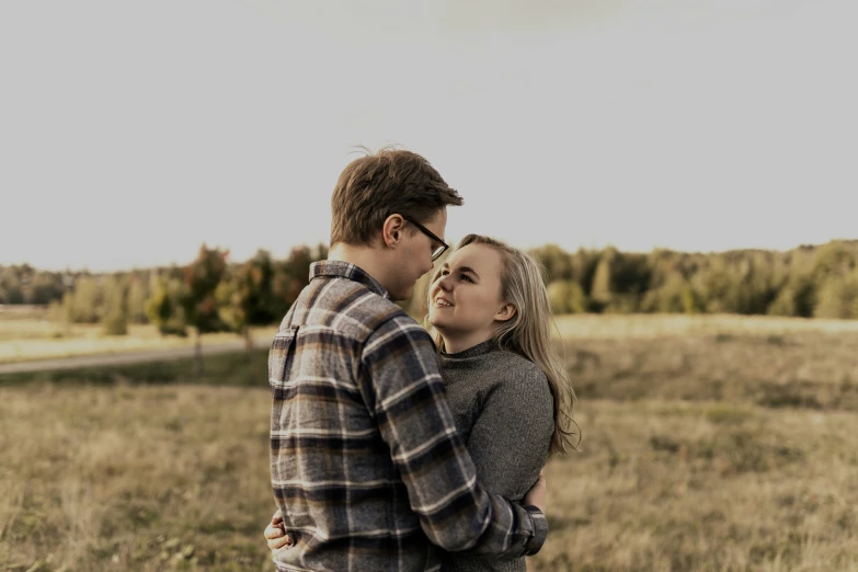 a woman standing next to a man in a field