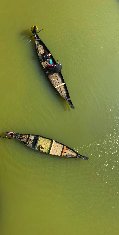 two people in canoes sit in the green water