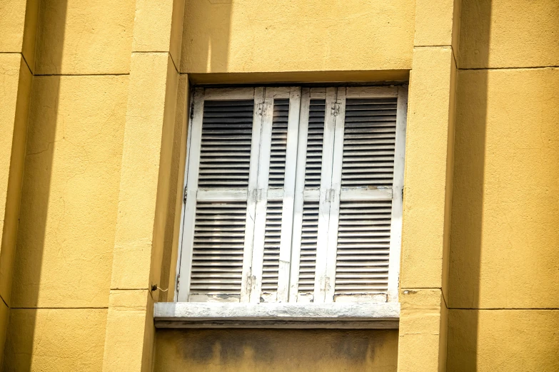 the window has white shutters and closed bars
