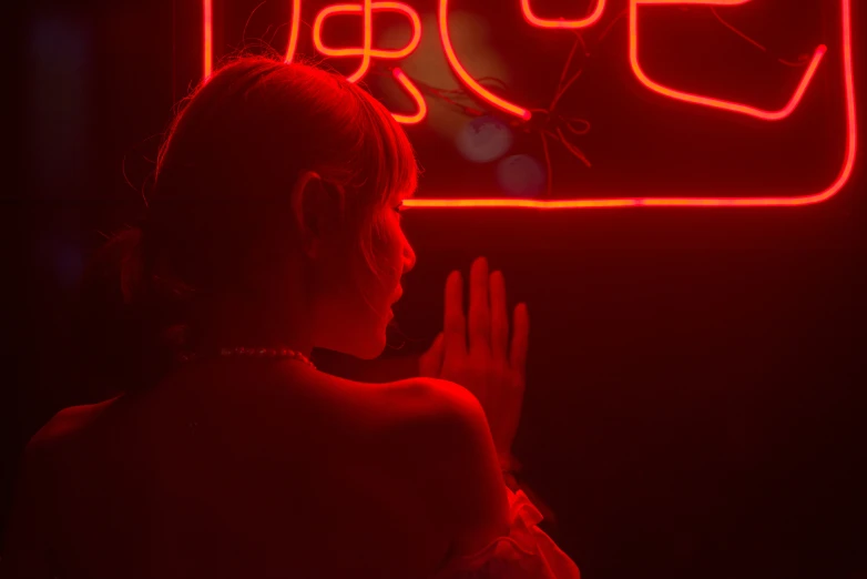 woman at night in dark room with neon sign