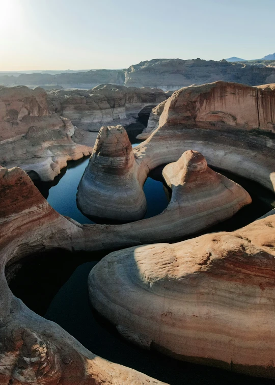 a small lake sits between large boulders and cliffs