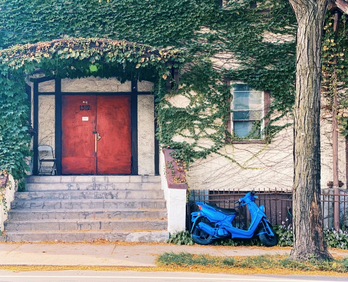 a bicycle parked on the sidewalk next to a house with ivy growing around it