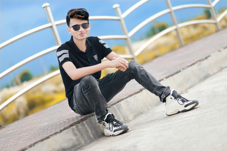 a boy is sitting on a ledge and leaning on the rail