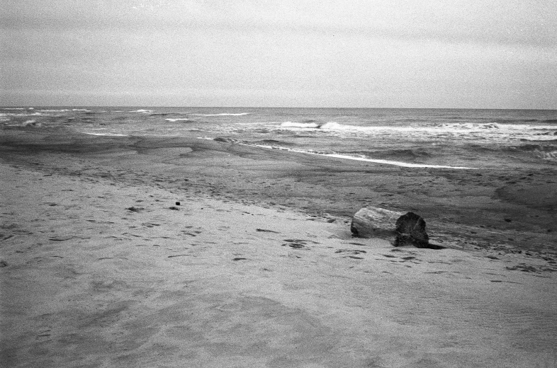 a lone surfer sitting on the edge of a body of water